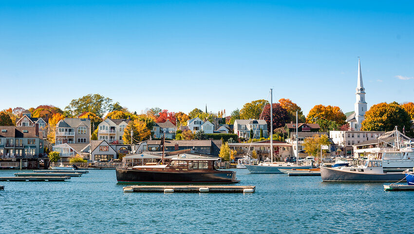 Camden, Maine harbor in autumn with boats and houses behind. 