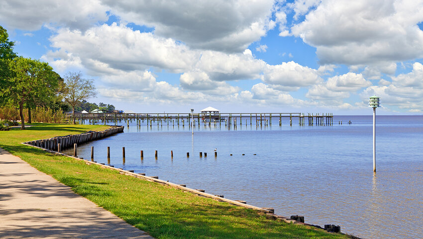 Walkway along the water with pier in distance. 