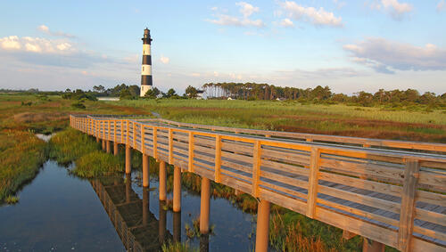 Wooden walkway from a viewpoint in the marsh leads to the Bodie Island lighthouse on the outer banks of North Carolina