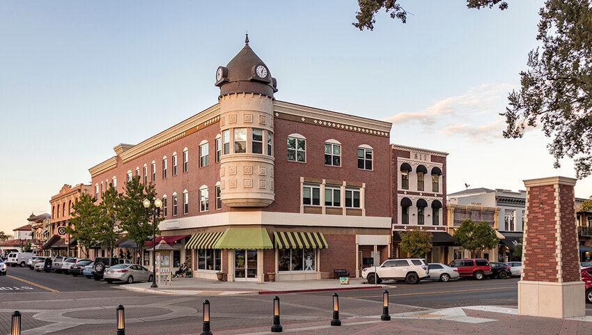 Downtown Paso Robles, with stores and parked cars, at sunset.