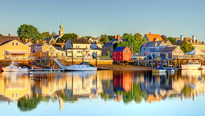 Docked boats and houses along water at sunset.