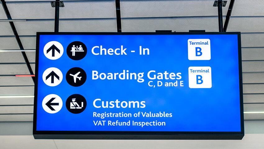 Info sign at international airport with directions to check-in, boarding gates, and customs.