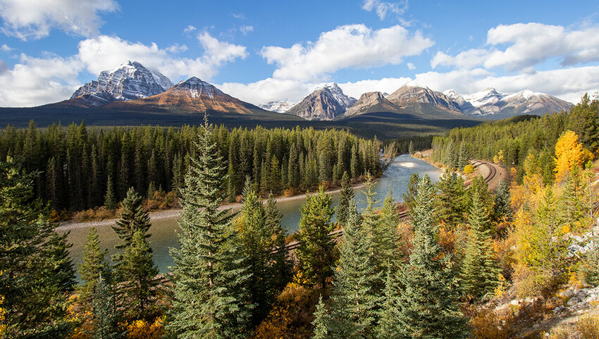 River through forest with mountains in distance during fall.