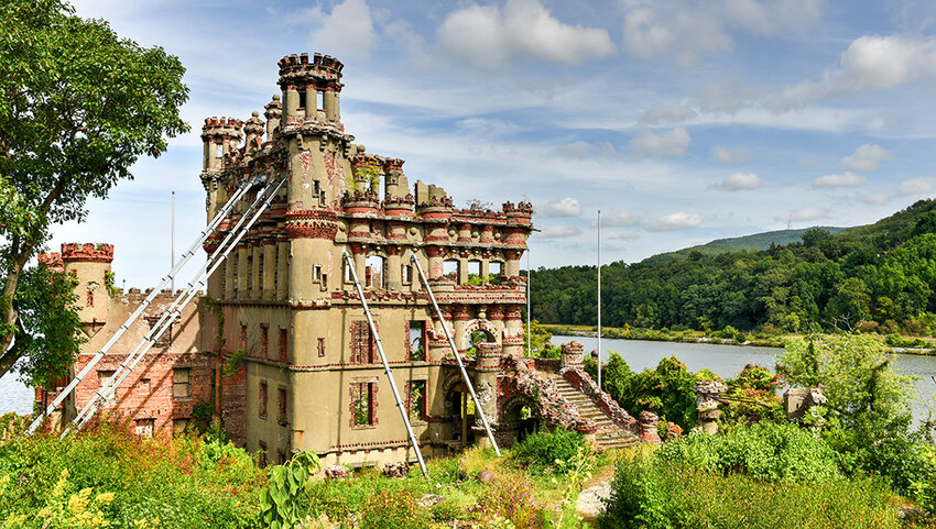 Castle near river with poles supporting it. 