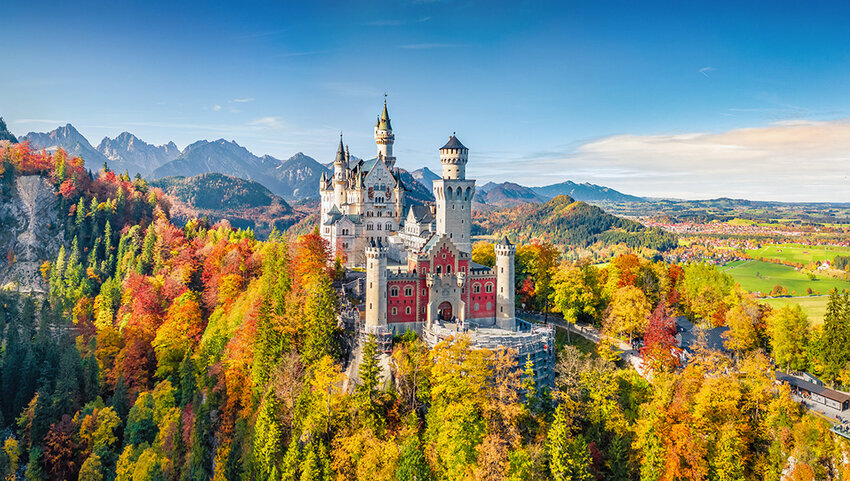 Aerial of Neuschwanstein Castle and surrounding fall foliage.