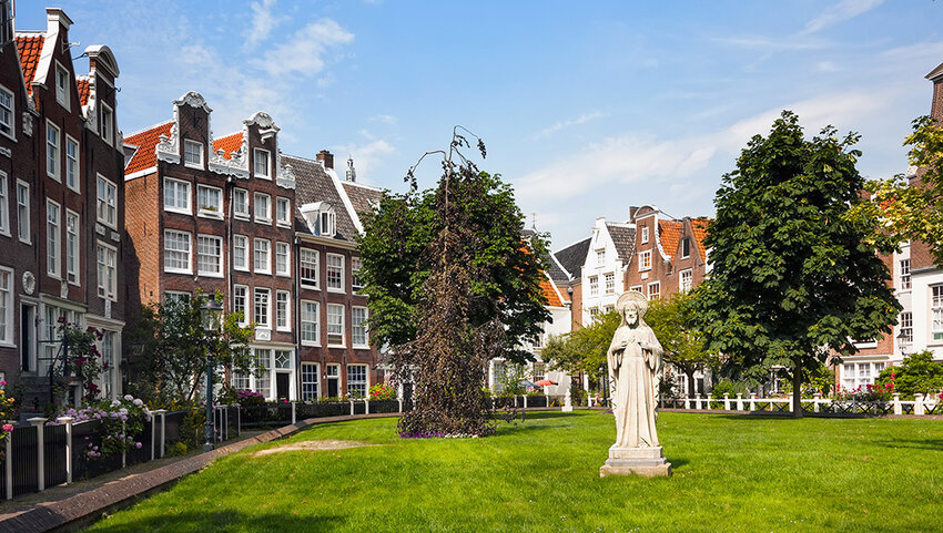 Statue and trees in courtyard surrounds by houses.