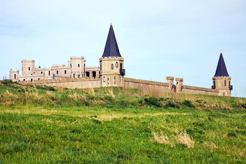 Castle and surrounding wall on grassy hill.