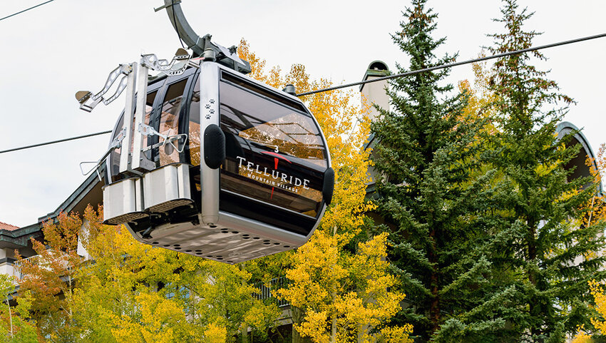 Telluride Mountain Village gondola cable car over fall foliage.