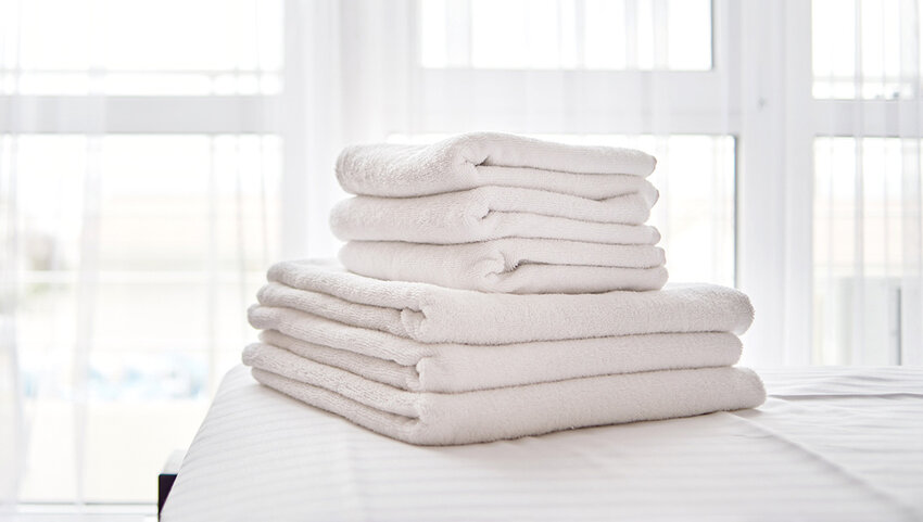 Stack of towels folded on bed.