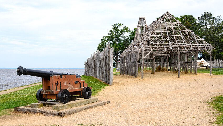 Cannon, fence, and wooden house structure in Jamestown National Historic Site.