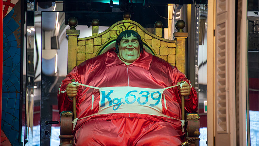 Mannequin of large man holding banner that says Kg. 639.