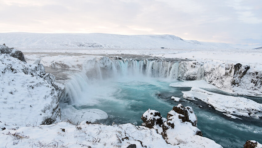 Snow covered land and waterfall.