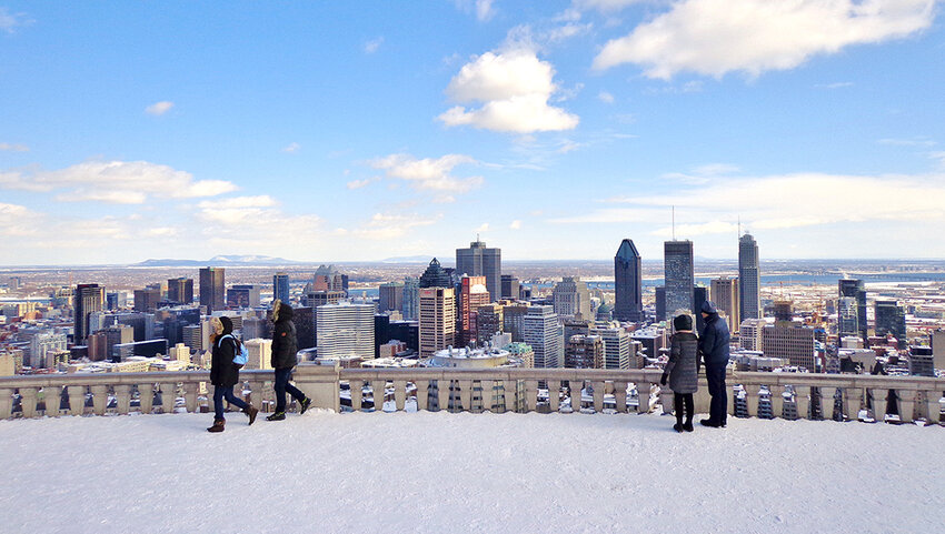 People on snow covered area overlooking Montreal skyline.
