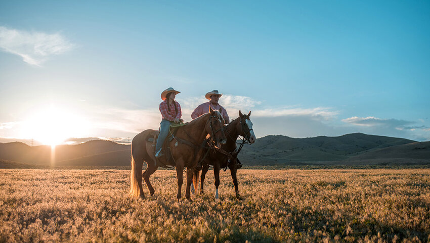 Mid adult couple relaxing while riding horses.