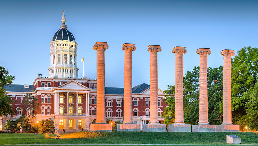 Row of columns and historic building at dusk.