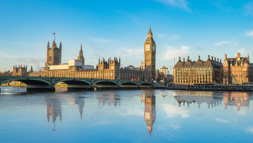 Big Ben and Westminster parliament with colorful sky and water reflection.