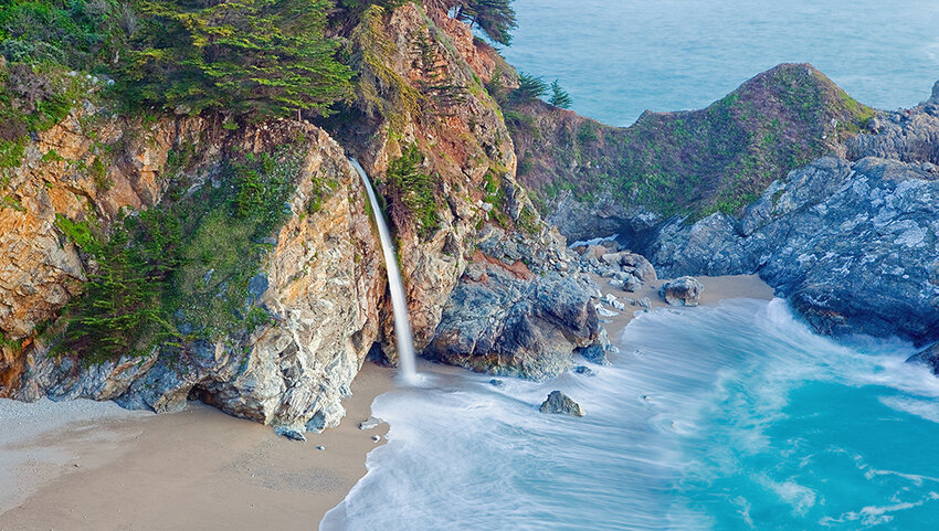 Waterfall through cliff into ocean. 