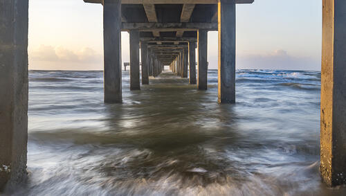 View of sunrise from under a pier. 